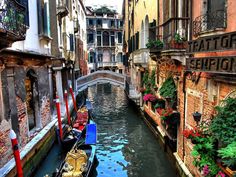 a narrow canal runs between two buildings with flowers on the balconies above them