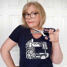 a woman wearing glasses and holding a pair of scissors