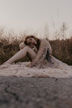 a woman is sitting on the ground with her arms around her neck and legs crossed