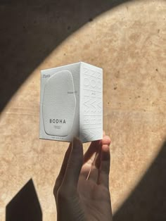 a person holding up a white box with the word boodia on it