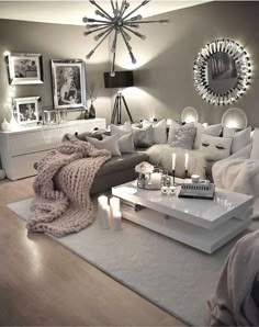 a living room filled with lots of white furniture and candles on top of a table