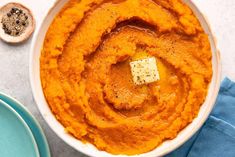 a bowl filled with mashed sweet potatoes and topped with a pate of butter