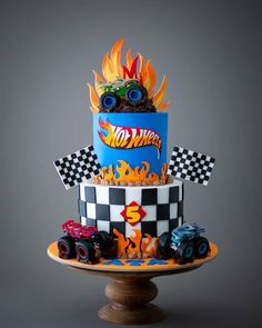 a three tiered cake with monster trucks on top and flames coming out of it