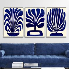 two blue and white paintings on a wall above a couch