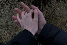 two hands reaching out to each other in front of some dry grass and bushes with their fingers together