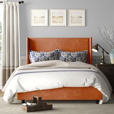 a bed with blue headboard and white sheets in a bedroom next to a window