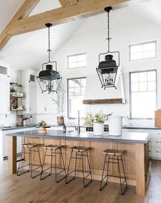 a kitchen island with stools and lights hanging from the ceiling