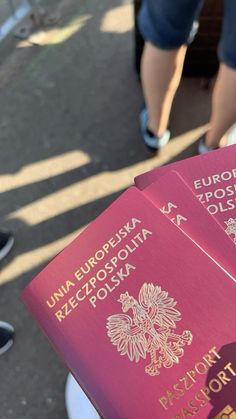 three red passports sitting on top of each other in front of people walking down the street