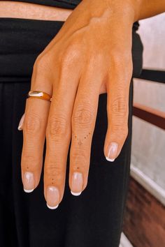 a woman's hand with a gold ring on her left wrist and black pants