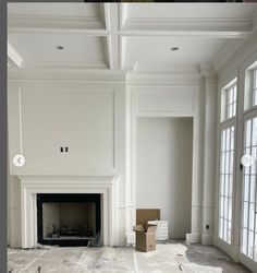 an empty living room with white walls and fireplace in the middle, surrounded by large windows