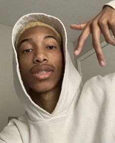 a man in a white hoodie pointing at the camera