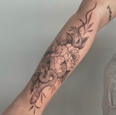 a woman with a snake and flowers tattoo on her arm