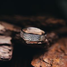 a silver ring sitting on top of a piece of wood