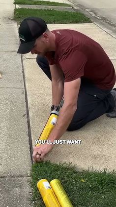 a man kneeling down on the sidewalk with two yellow baseball bats in front of him