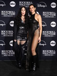 two women standing next to each other on a black carpet with the words rock roll hall fame