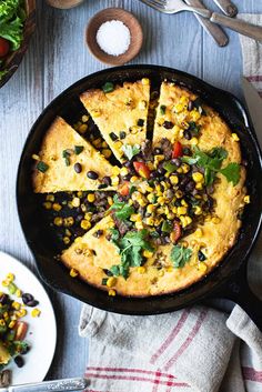 a skillet filled with corn and black beans next to a plate full of salad