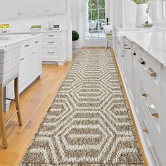 a kitchen with white cabinets and an area rug that looks like hexagonal tiles