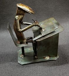 a metal figurine sitting at a desk with a mouse on it's back