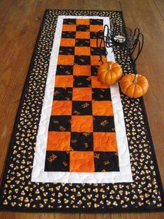 an orange and black table runner with pumpkins on the floor in front of it