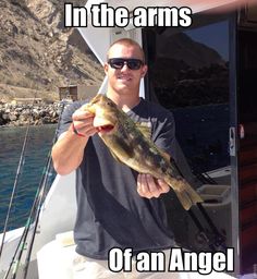 a man holding a fish in his hand while standing on a boat with the caption, in the arms of an angel