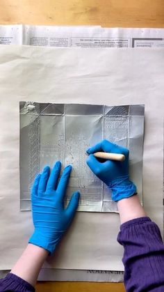 a person in blue gloves is working on a piece of paper that has been cut into squares