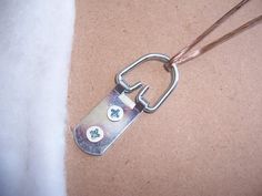 a close up of a metal object on a brown surface with a chain attached to it