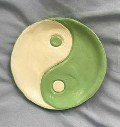 a green and white yin - yang dish sitting on a bed