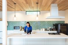 a woman is standing at the kitchen counter in front of an oven and stove top