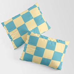 two blue and yellow checkered pillows sitting on top of each other in front of a white background