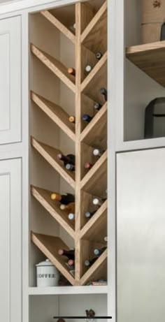 a kitchen with white cupboards and shelves filled with wine bottles in the bottom half