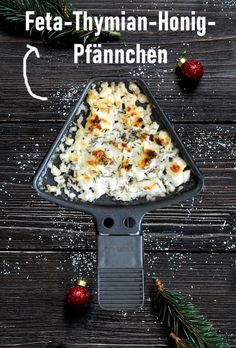 a pan filled with food on top of a wooden table next to pine cones and christmas decorations