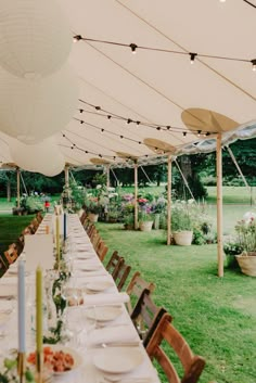 a long table is set up for an outdoor party with white paper lanterns and hanging lights