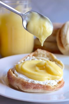 a spoon with some food on top of it next to bread and orange juice in the background