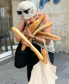 an older woman carrying bread sticks in her hand