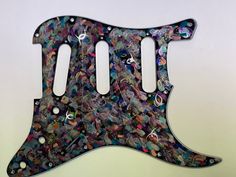 a guitar pick up plate with many different designs on it's back and sides