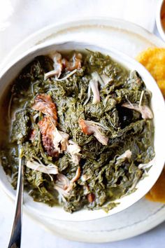 a white bowl filled with spinach and meat next to other foods on a table