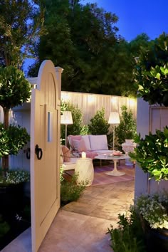 an open door leading to a patio with furniture and trees in the background at night