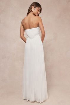 a woman in a white dress is looking down at the back of her wedding gown