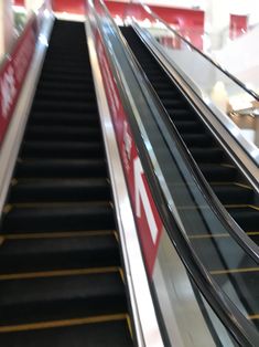 an escalator in a shopping mall with signs on the railings and stairs