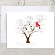 a red bird sitting on top of a tree next to a white card and envelope