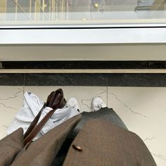 a man's suit and shoes sitting on the ground in front of a window