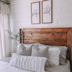 a bed with two framed pictures above it and pillows on the headboard, in front of a window