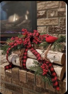 a red bird sitting on top of a log next to a fire place with christmas decorations