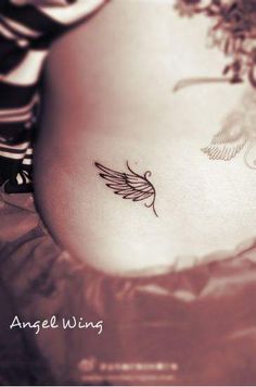 a woman's stomach with a small tattoo on the side of her belly and an angel wing