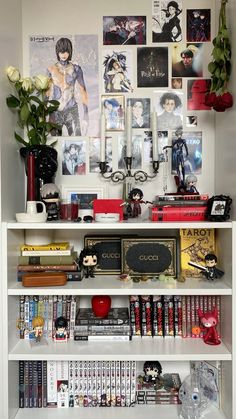 a book shelf filled with lots of books and pictures on the wall next to vases