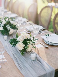 the table is set with white flowers and greenery for an elegant dinner or reception