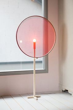 a red lamp sitting on top of a white floor next to a window in a room