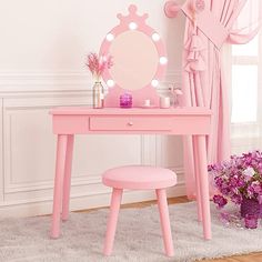 a pink vanity table with a mirror and stool in front of it, next to a window