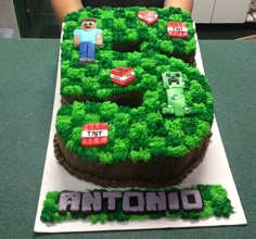 a cake that is shaped like the number five with legos on it and green grass