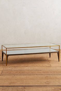 a glass and brass coffee table on wooden floor